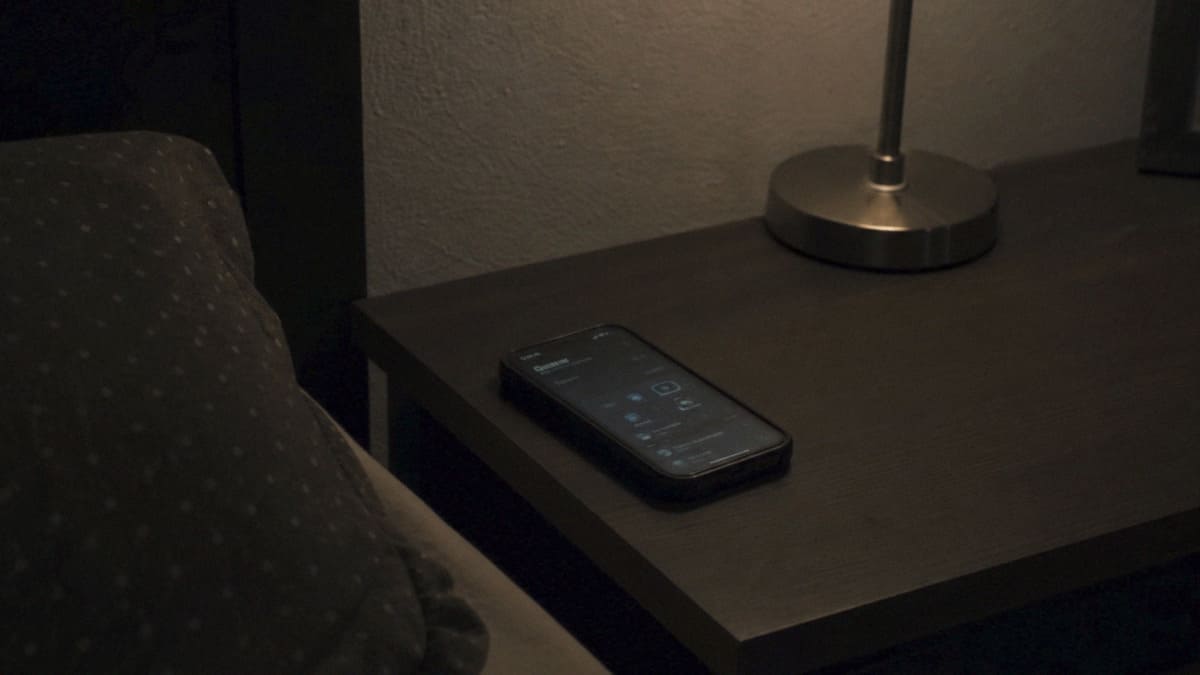 A phone on a bedside table at night, screen still active